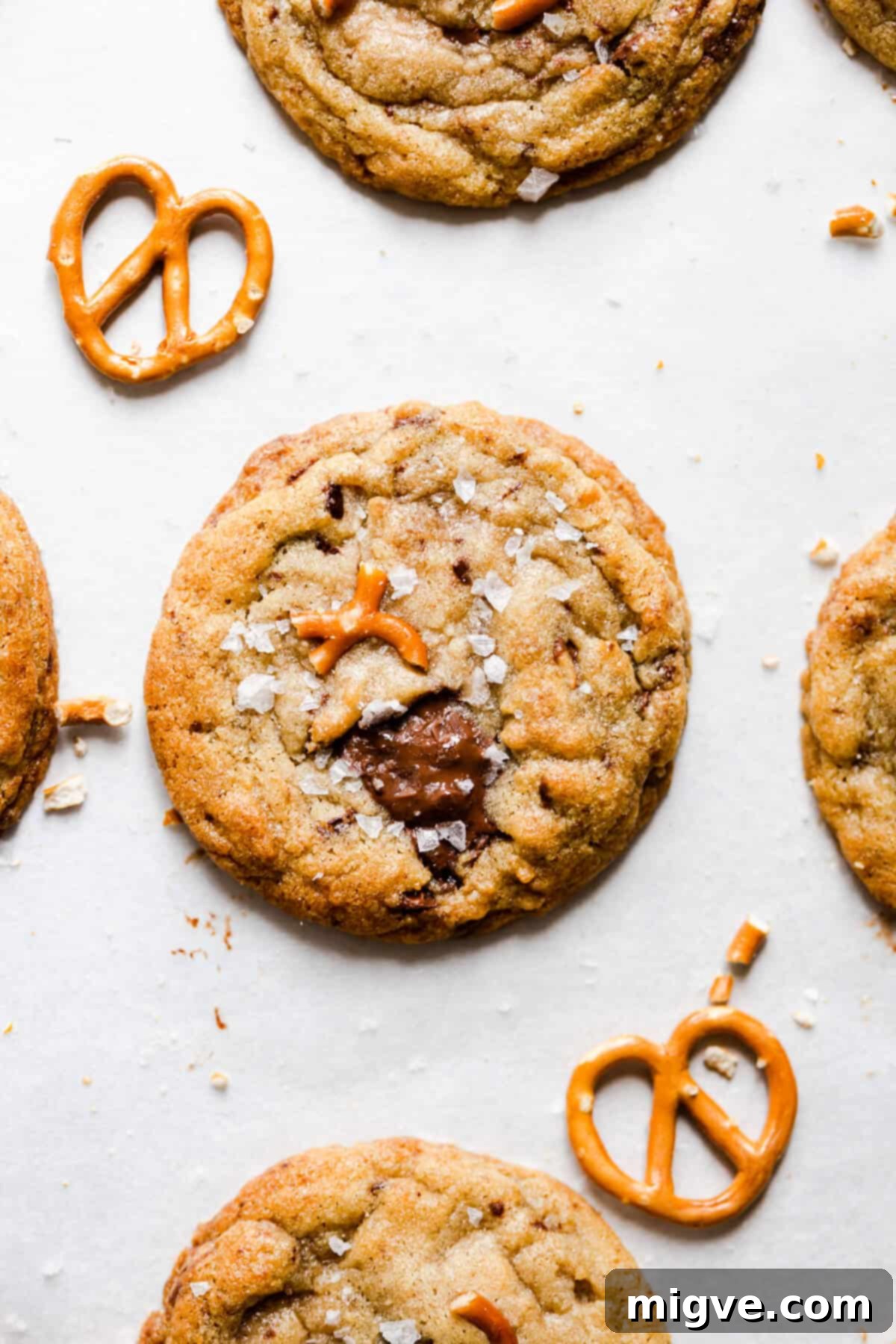 Close-up top view of freshly baked chocolate pretzel cookies, adorned with generous chunks of chocolate, crispy pretzels, and a delicate sprinkle of sea salt.
