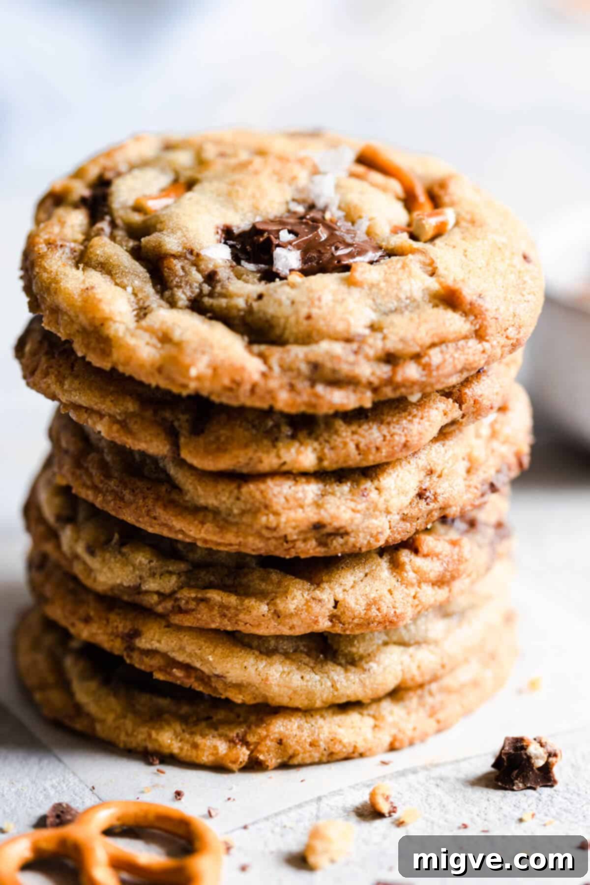 Super close-up of a stack of three chocolate pretzel cookies, revealing their rich texture, molten chocolate chunks, and embedded pretzel pieces.