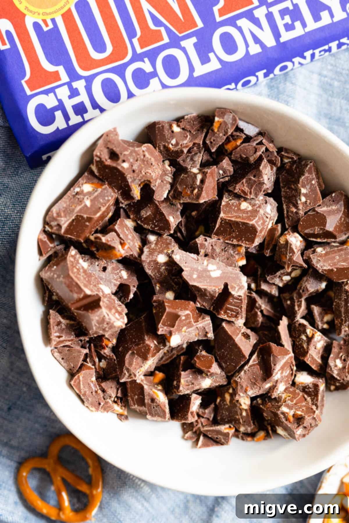 Close-up top view of a bowl filled with roughly chopped dark chocolate and pretzel pieces, ready to be incorporated into cookie dough.