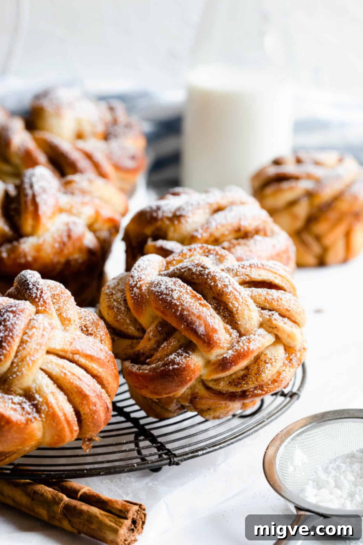 side shot of cinnamon buns shaped into knots and dusted with icing sugar