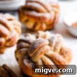 side close up of cinnamon bun twisted into a knot with icing sugar on top