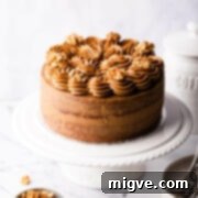 coffee and walnut cake topped with buttercream and nuts on a white cake stand.