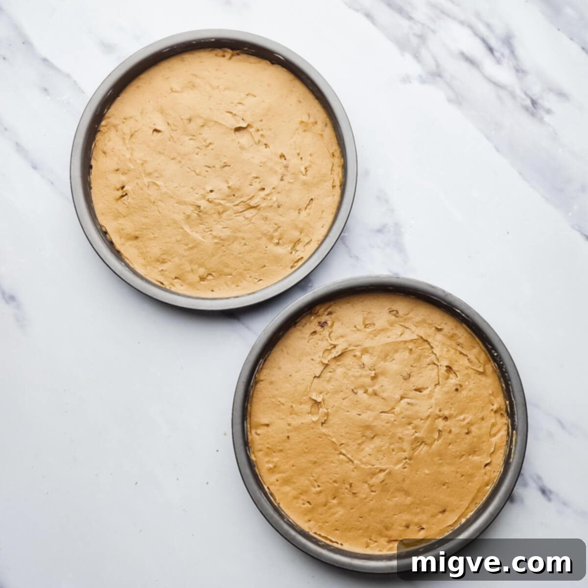 two round baking tins with cake batter inside.