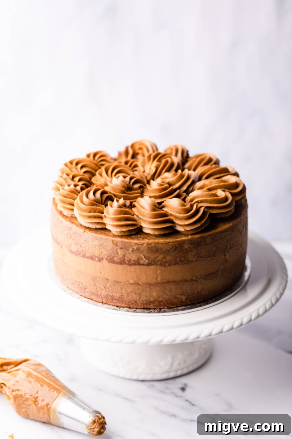 coffee and walnut cake on a white cake stand.
