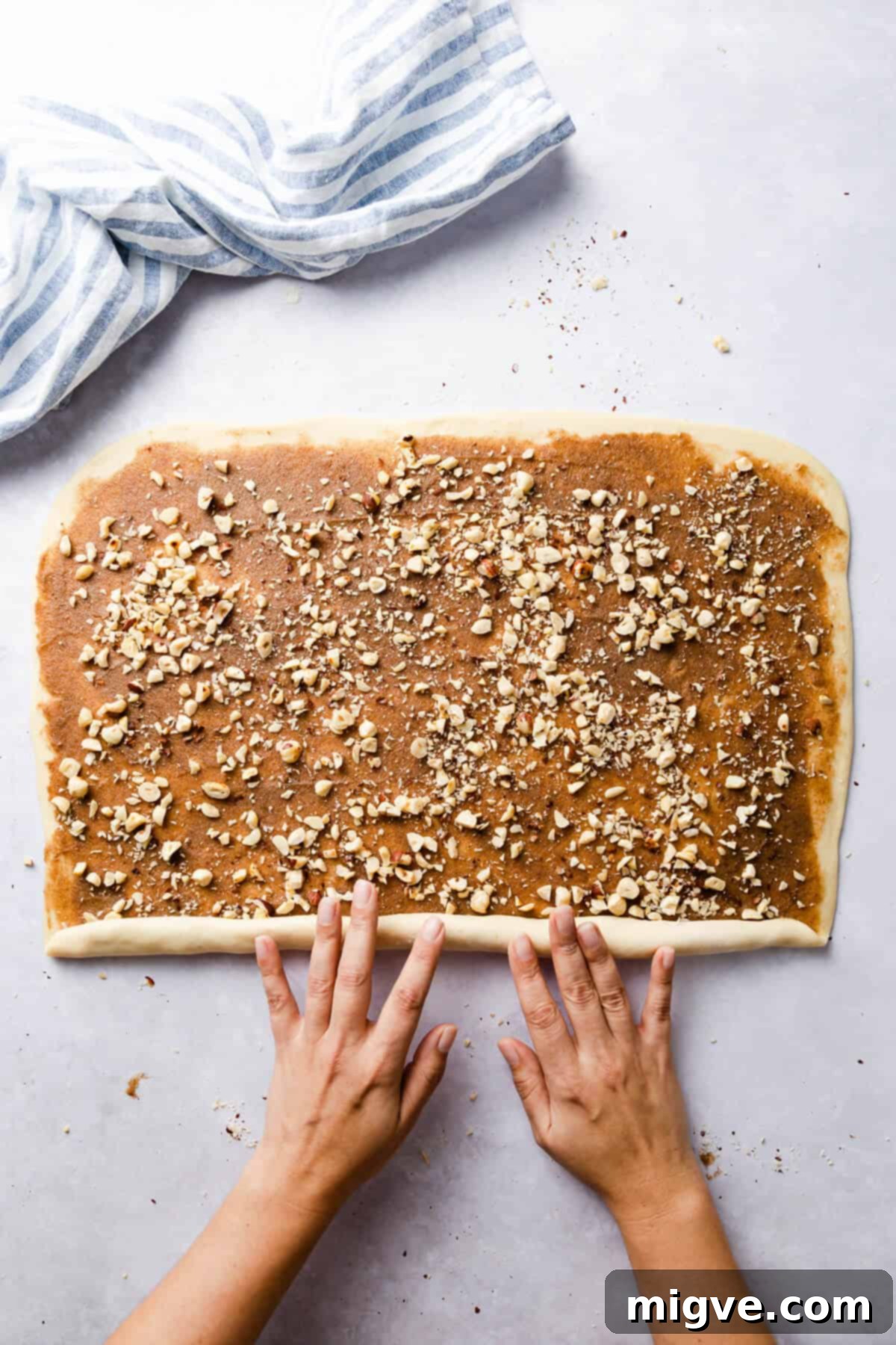 top view of a person rolling the dough for twisted cinnamon and hazelnut bread into a log