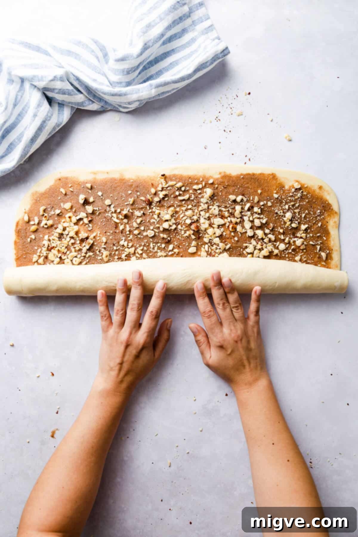 top view of dough for twisted cinnamon and hazelnut bread being rolled into a large log