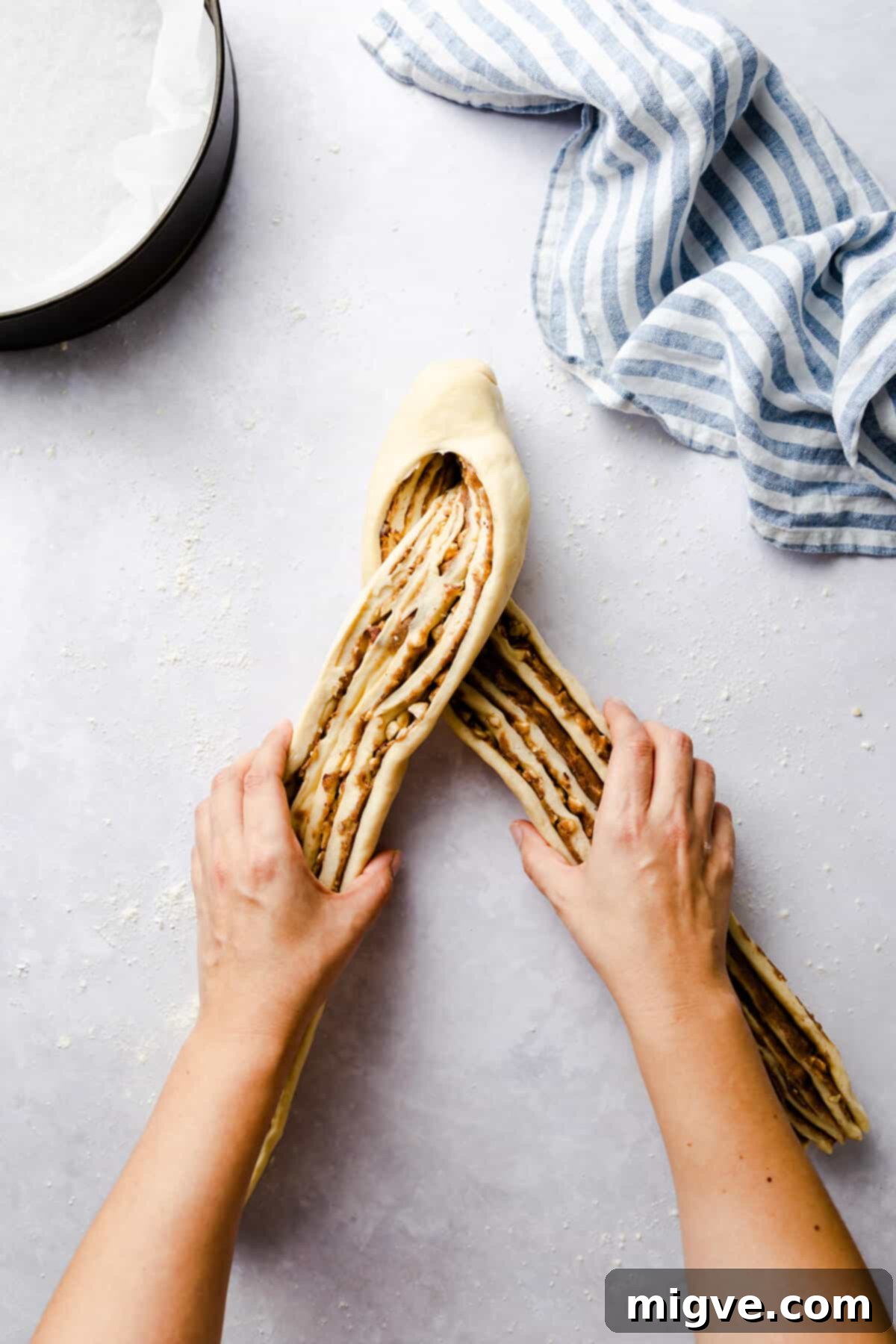 top view of a person shaping a sliced log of dough into a cross pattern
