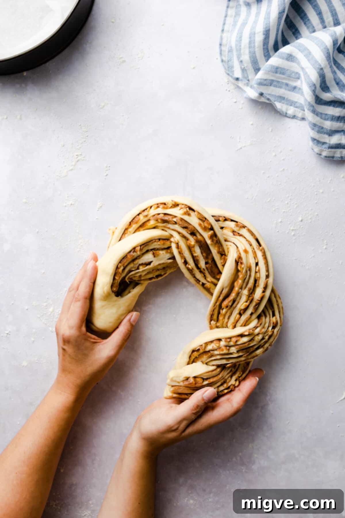 overhead shot of a person shaping twisted cinnamon bread into a circle