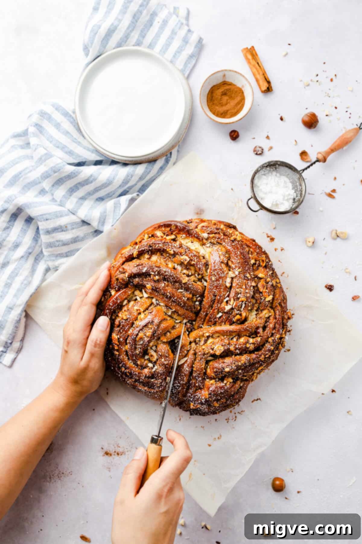 top view of a person slicing into cinnamon bread dusted with icing sugar