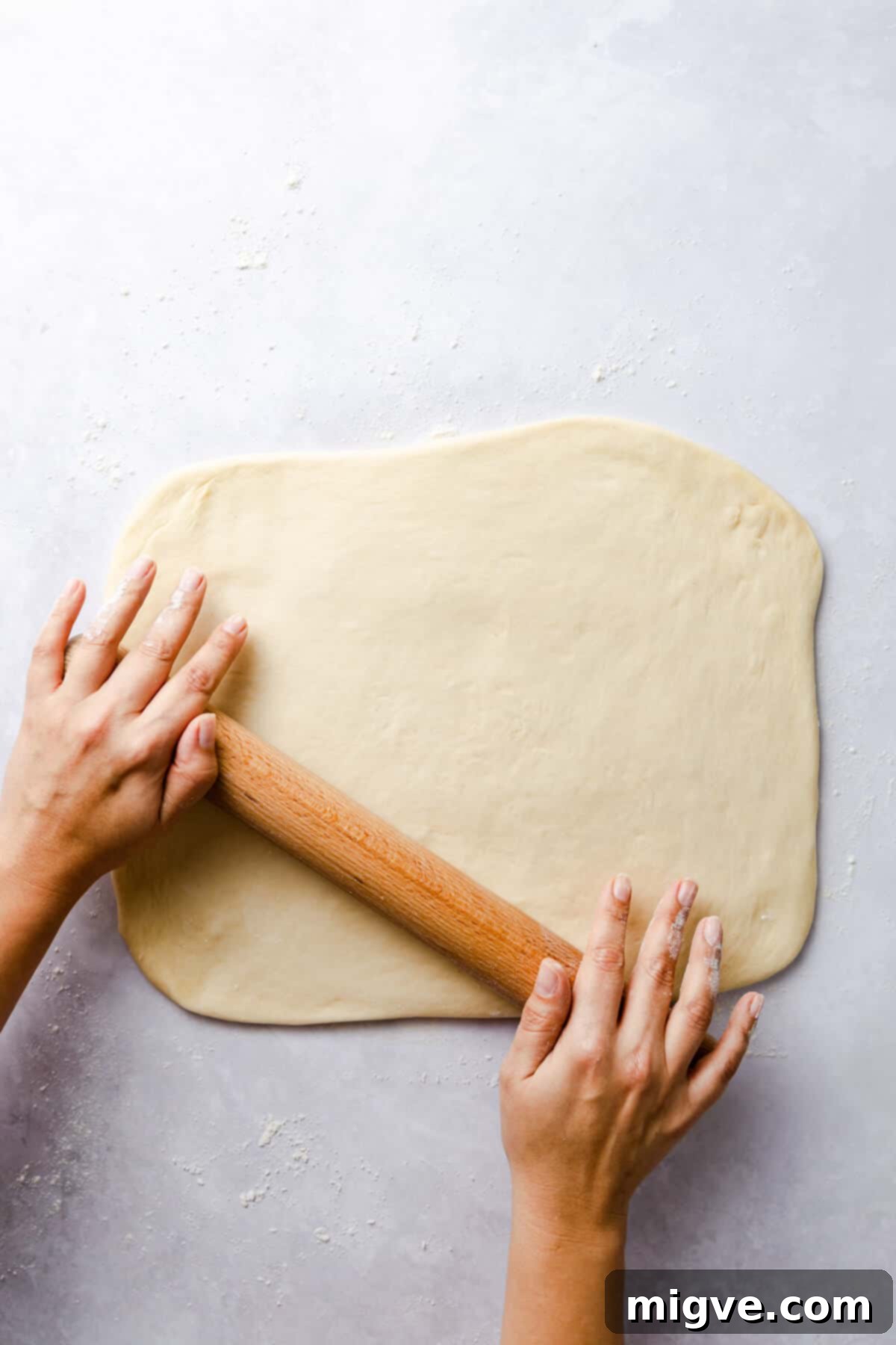 top view of a person rolling the dough into rectangle with rolling pin