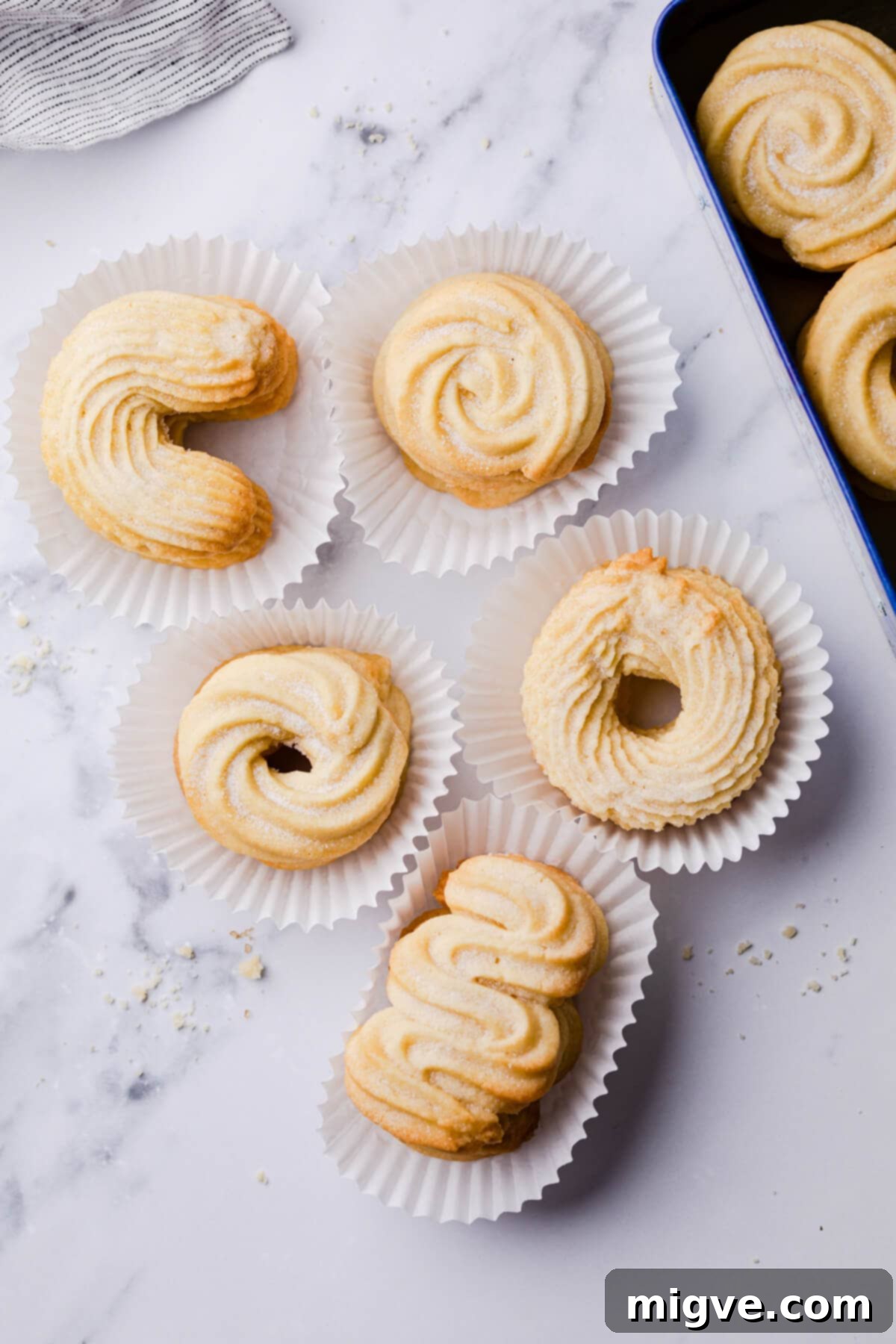 Buttery Danish Cookie Perfection 12 An inviting variety of Danish butter cookies, each nestled in its own paper liner, showcasing their beautiful shapes.