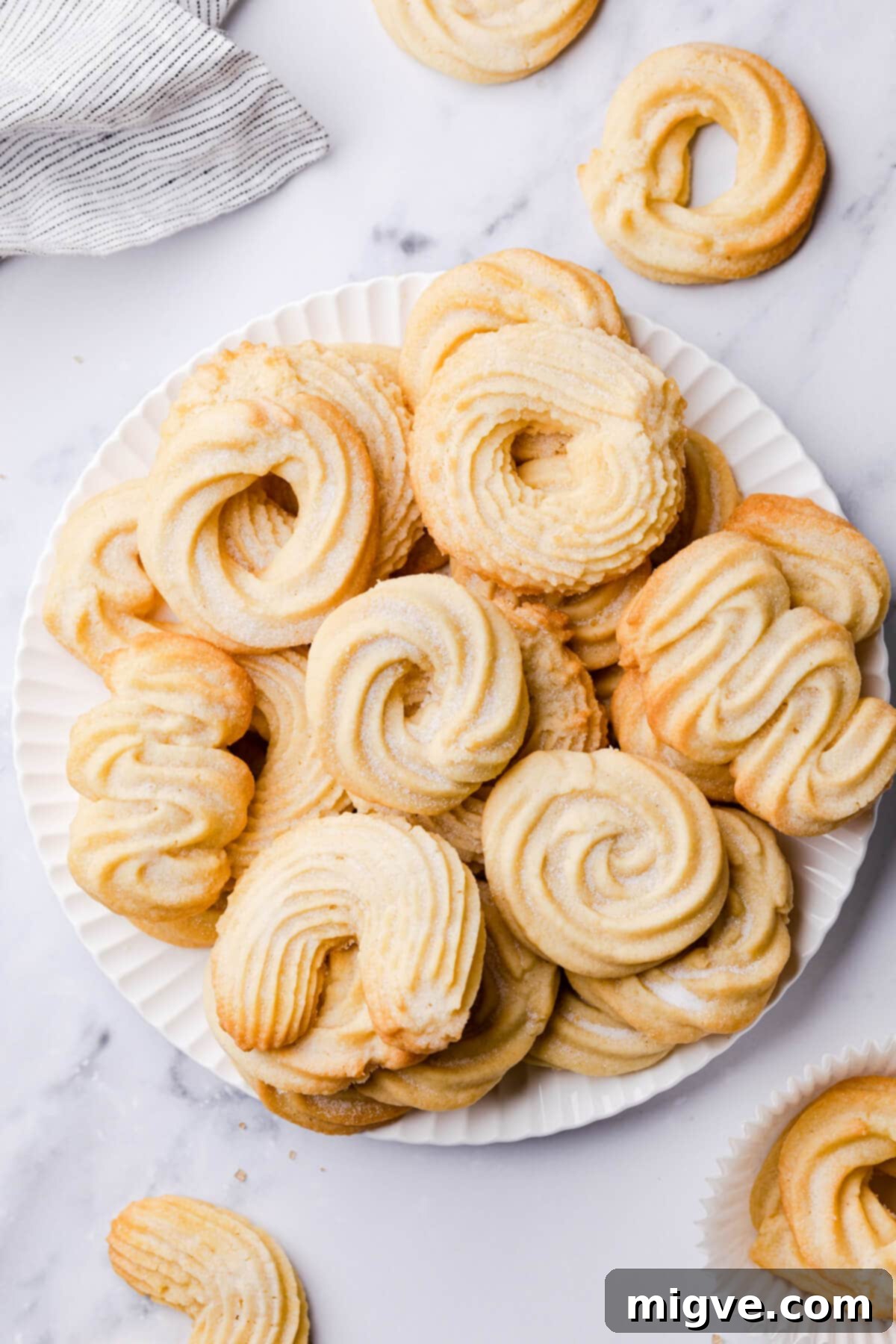 Buttery Danish Cookie Perfection 8 A charming selection of Danish-style butter cookies in various elegant shapes displayed on a pristine white plate.