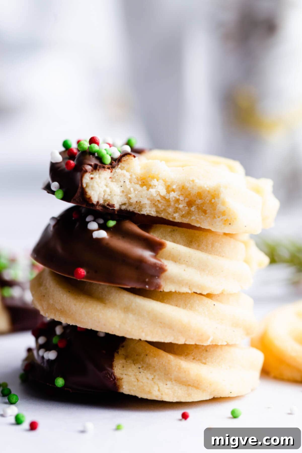 Buttery Danish Cookie Perfection 9 A stack of four perfectly baked butter cookies, with the top cookie having a delightful bite taken out of it.