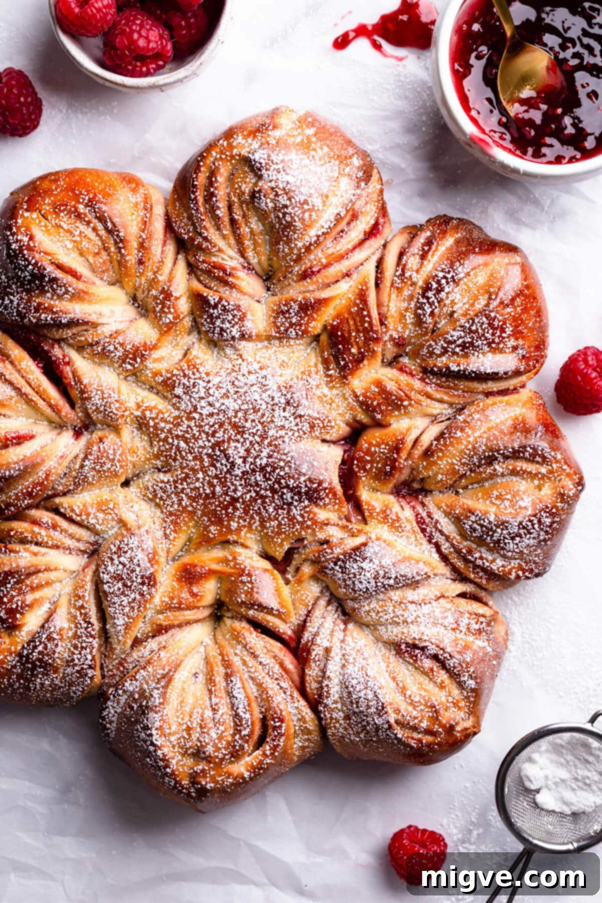 overhead close up at a raspberry star bread with icing sugar on top