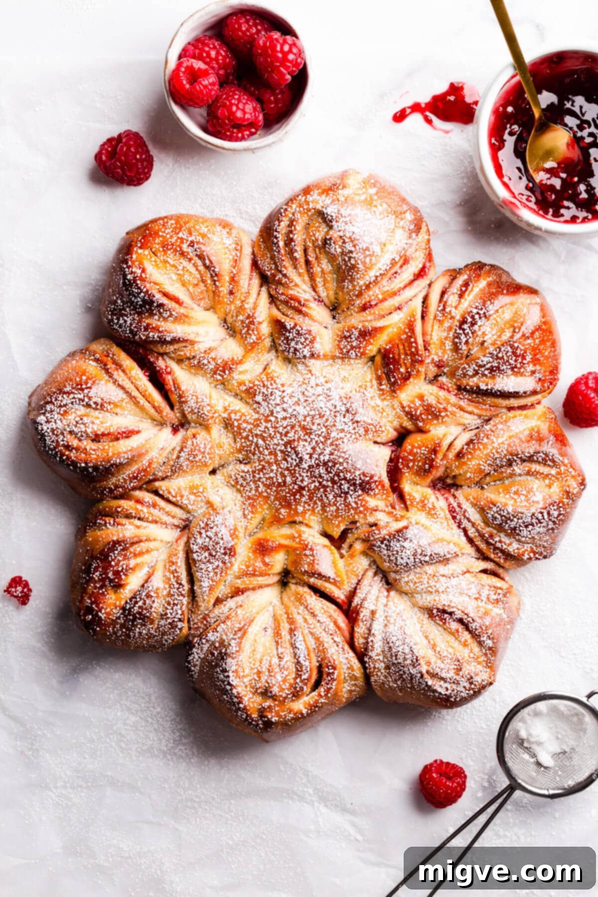 overhead view of a star bread with raspberry jam and sugar dusting