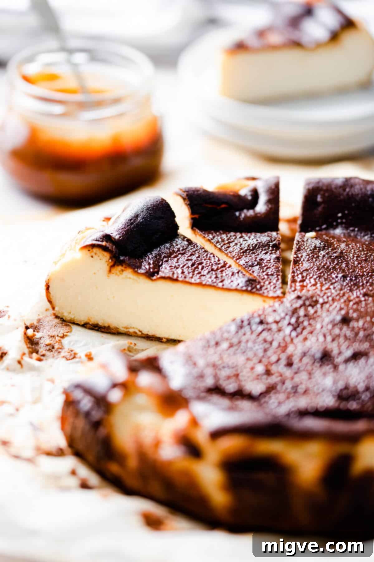 45 degree side shot of burnt basque cheesecake with couple of slices cut out, showcasing its iconic burnt exterior and creamy interior.