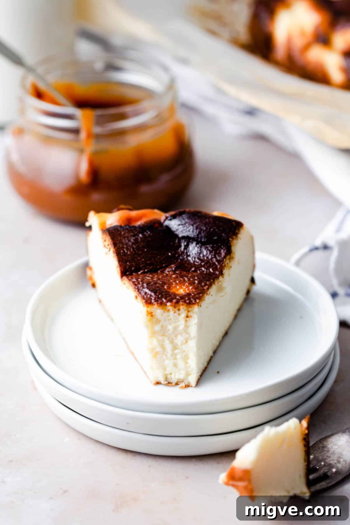 straight ahead close up of a slice of cheesecake with a bite missing, revealing the creamy texture and burnt exterior.