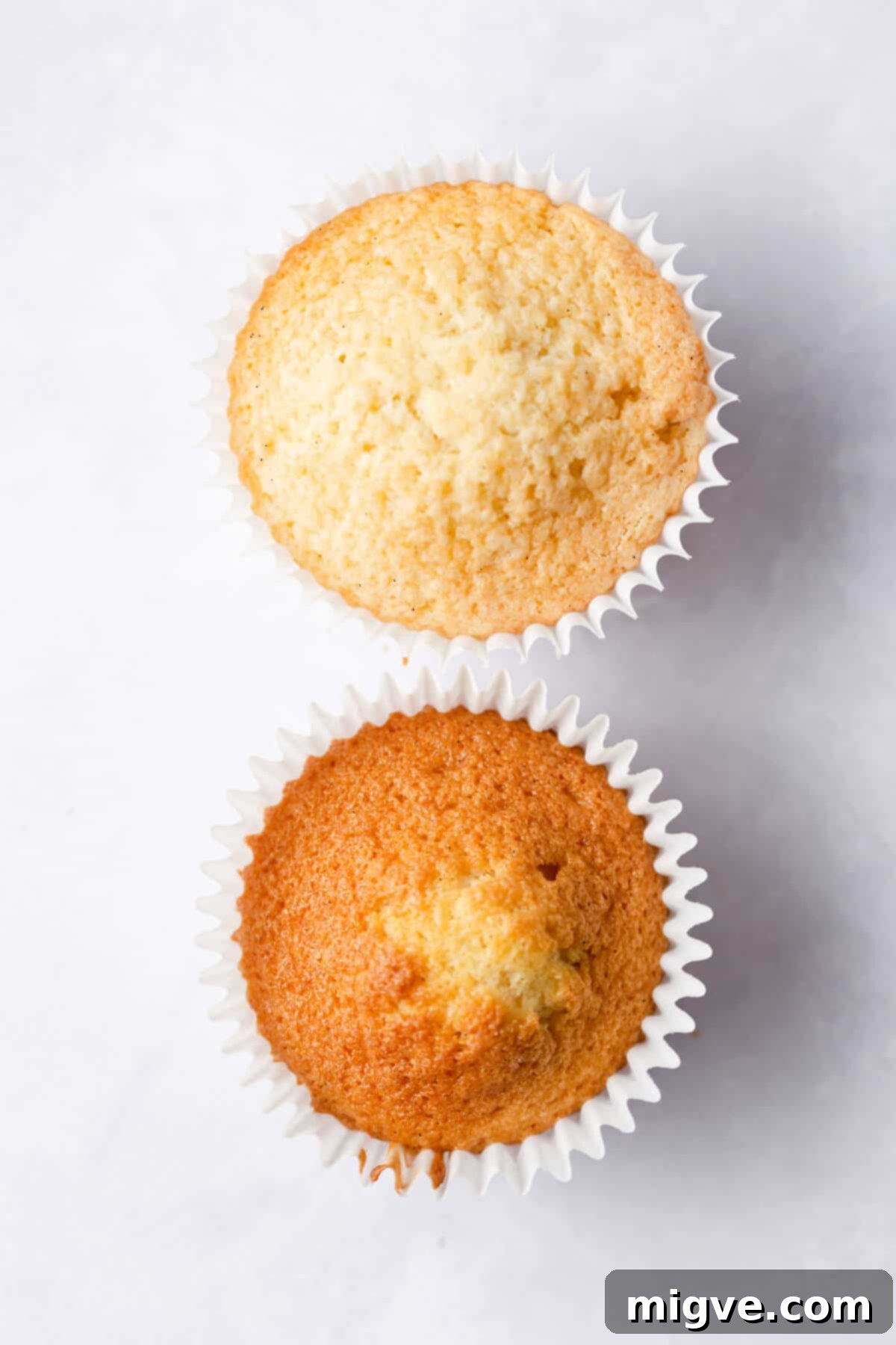 A top-down view of two cupcakes, one showing an under-baked, pale top with a hard crust, and the other an uneven, dark-crusted top with a hump, illustrating common baking mistakes.