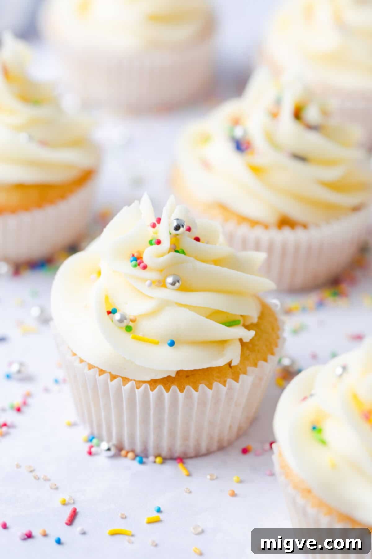 A 45-degree angle photo of a beautifully decorated one-bowl vanilla cupcake, generously topped with creamy buttercream and vibrant sprinkles, ready to be enjoyed.