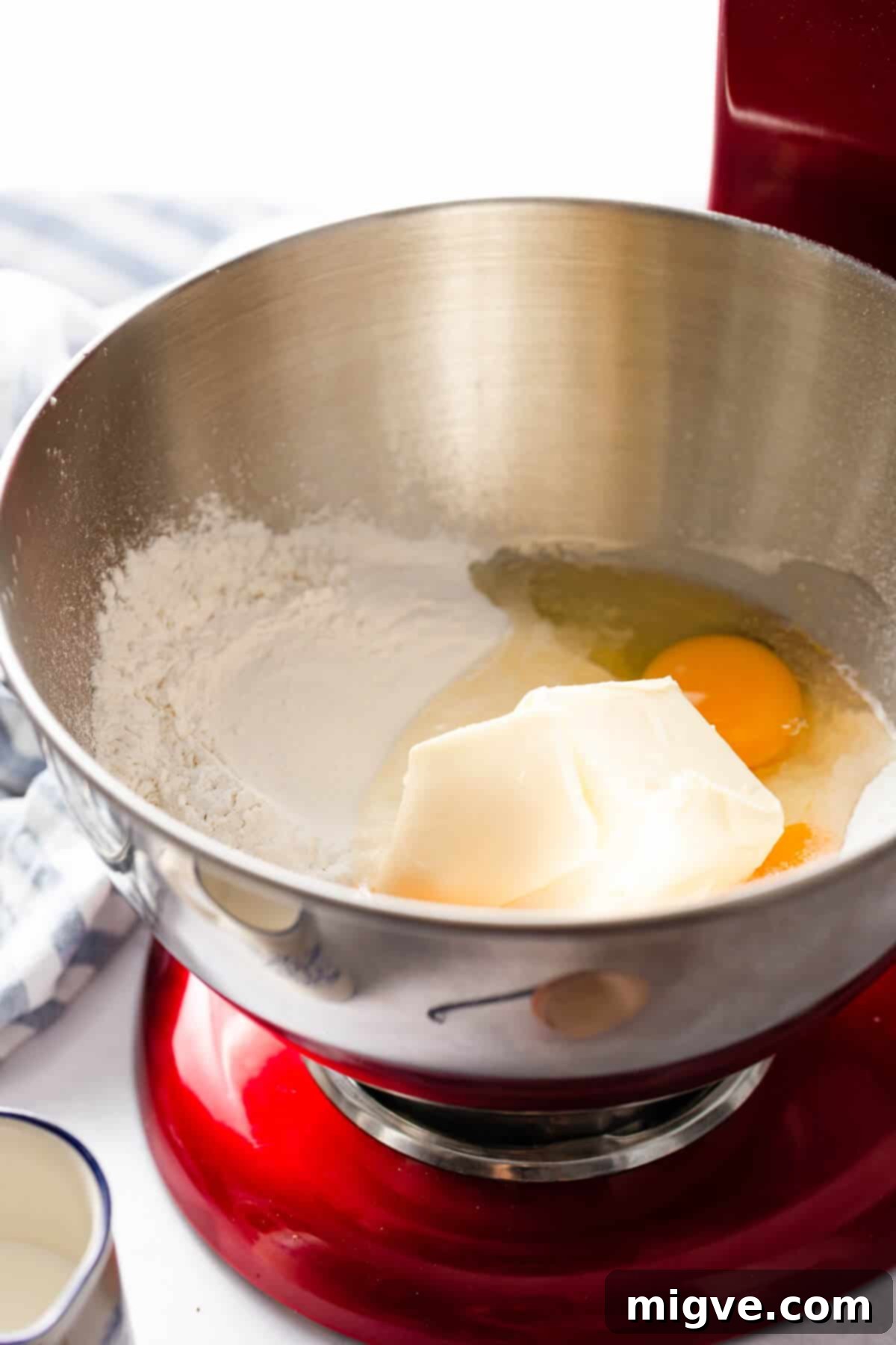 A side-angle photo of a metal mixing bowl containing the initial sifted dry ingredients for cupcakes, ready for the next steps of the baking process.