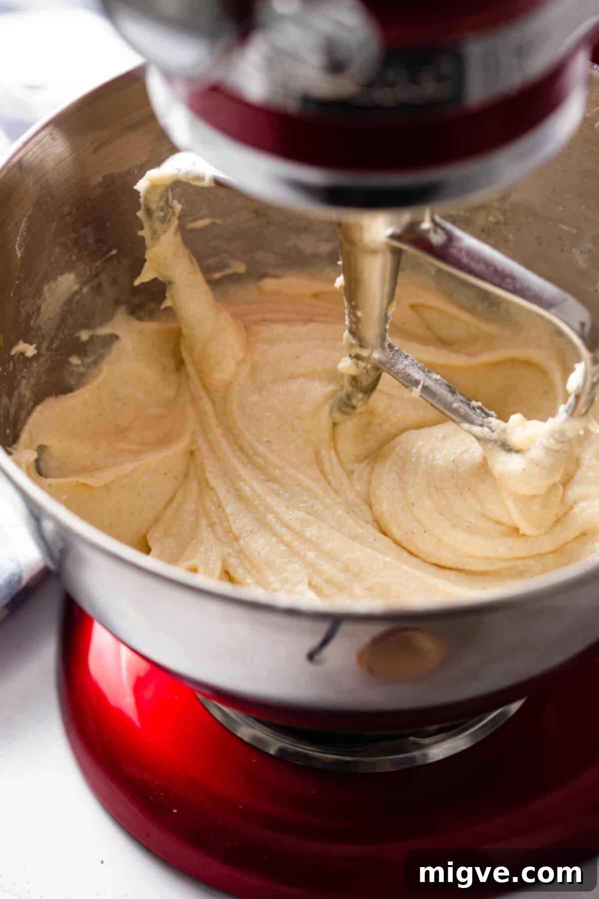 A close-up side view of a mixing bowl filled with smooth, creamy cupcake batter, highlighting its perfect consistency and readiness for baking.