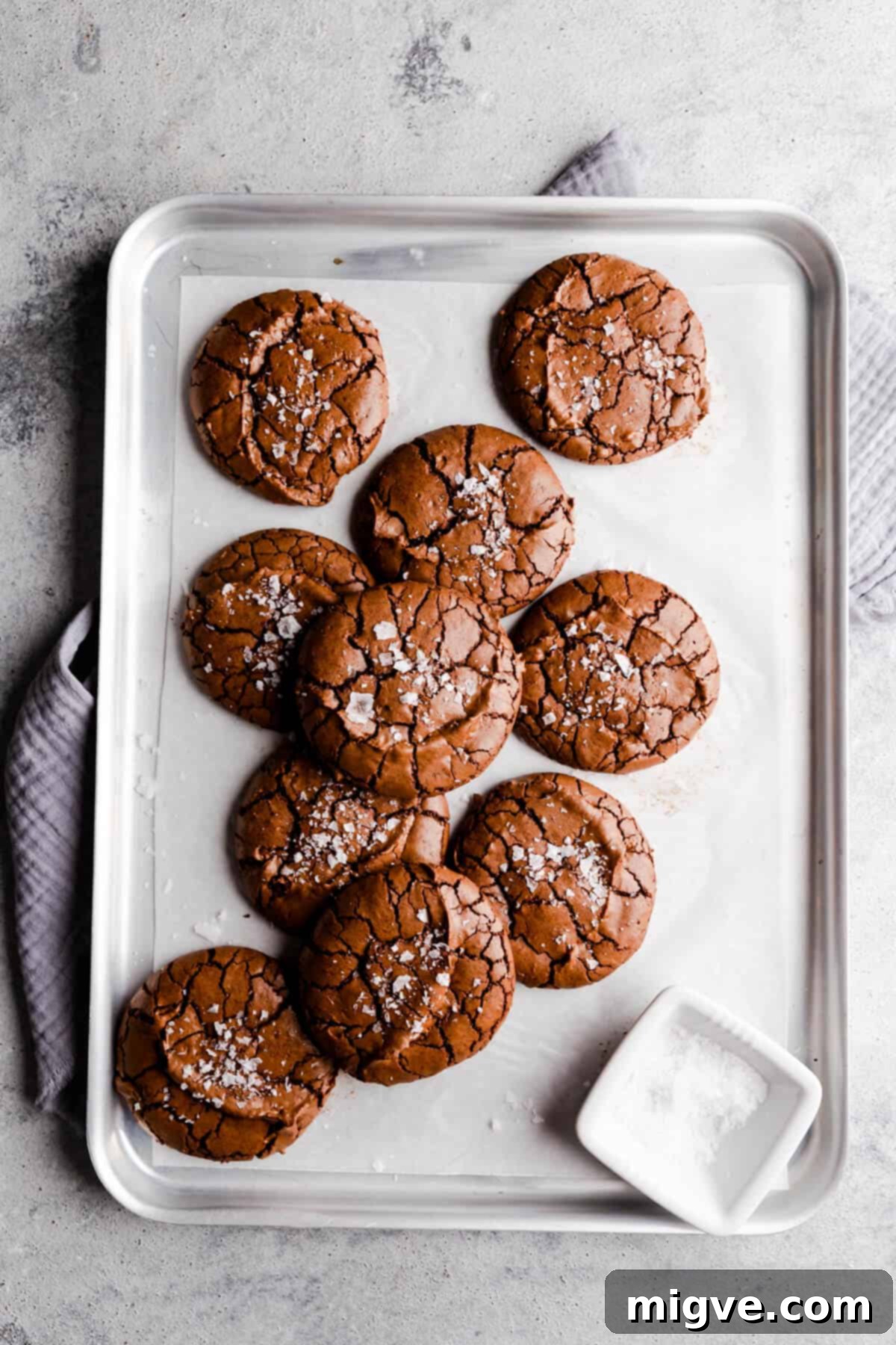 overhead shot of 10 chocolate brownie cookies on silver baking tray with some sea salt
