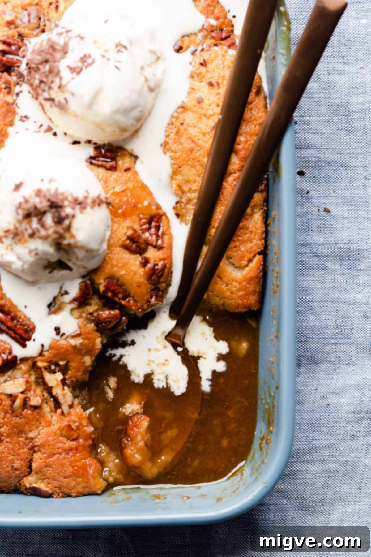 Super close-up, top-down view of a baking dish filled with self-saucing banana pudding, with a portion already served, inviting you to dig in