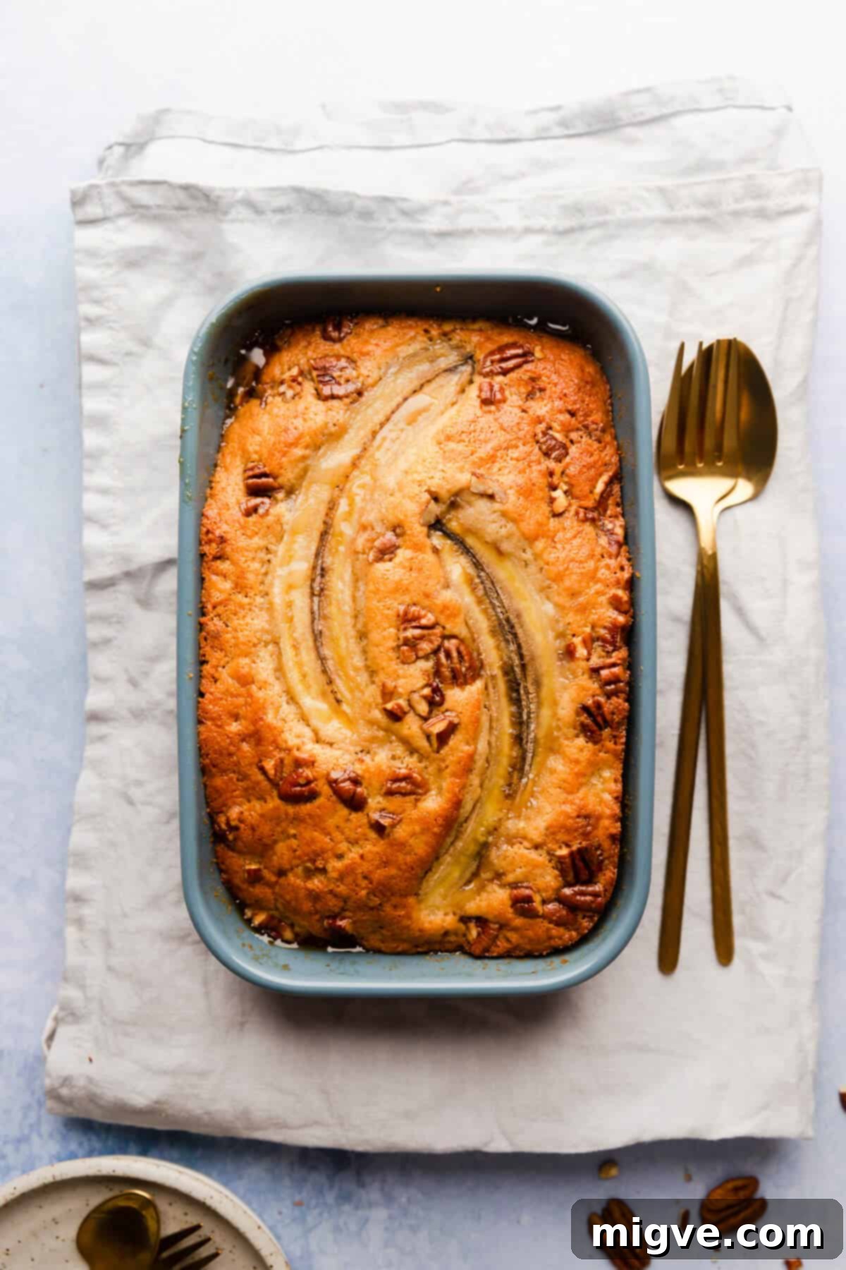 An inviting overhead shot of self-saucing banana pudding, beautifully garnished with fresh banana slices and crunchy pecans