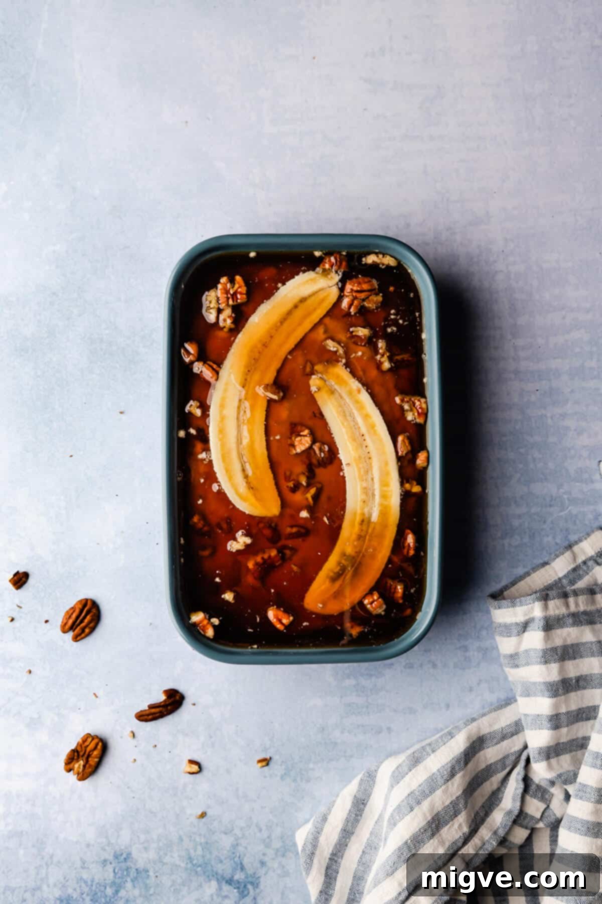 Overhead shot of a baking dish filled with self-saucing banana pudding batter, now covered with the hot liquid topping, poised for baking