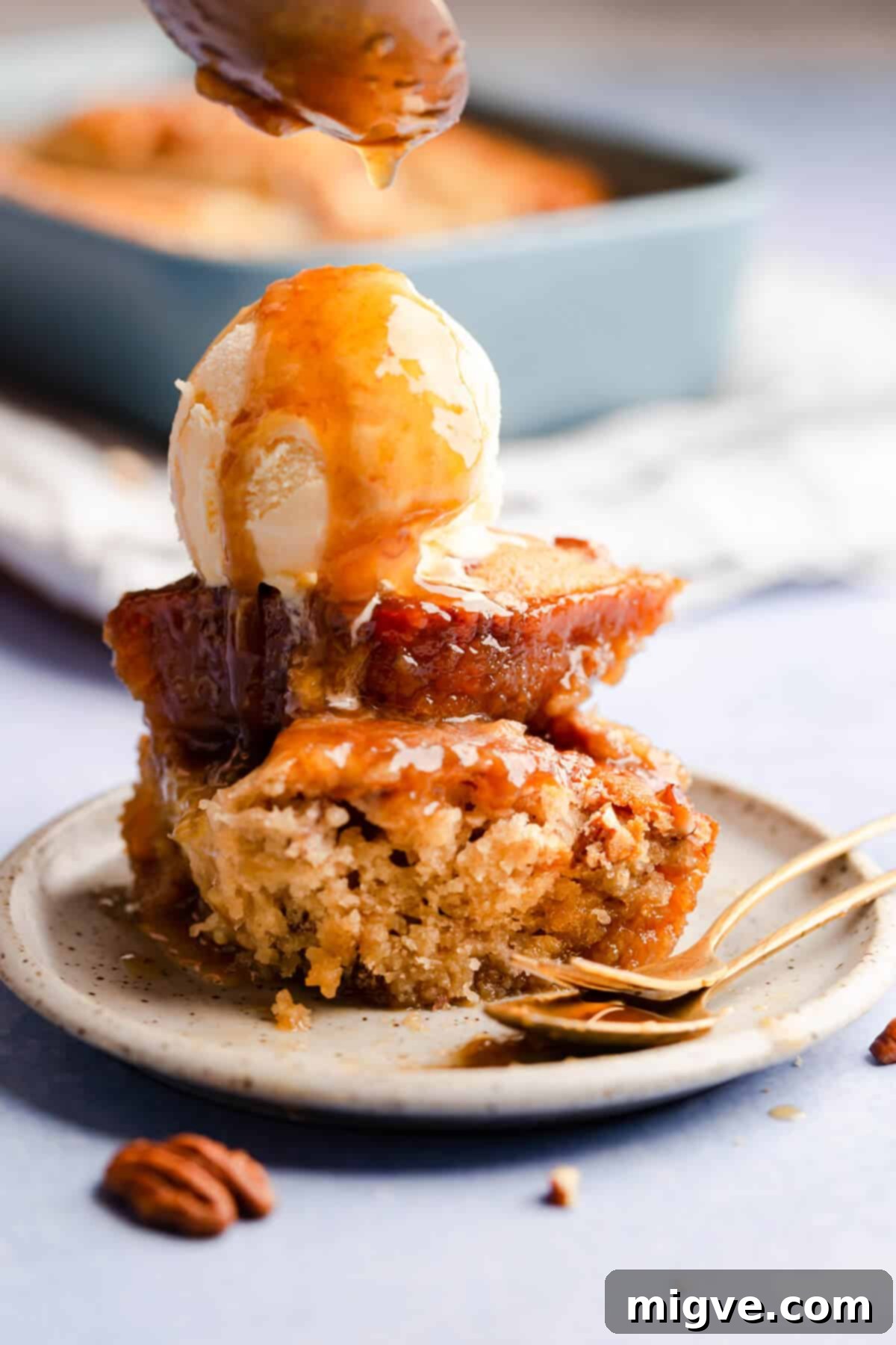 A delightful side angle view of a portion of banana pudding topped with creamy ice cream, exquisitely drizzled with its signature sticky sauce