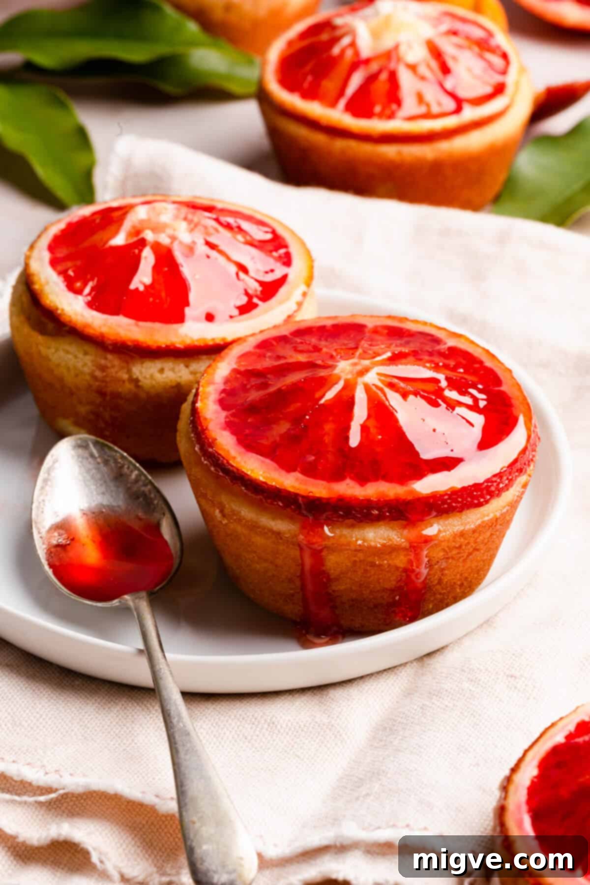 side super close up at two mini cakes topped with blood orange slices and drizzled with syrup