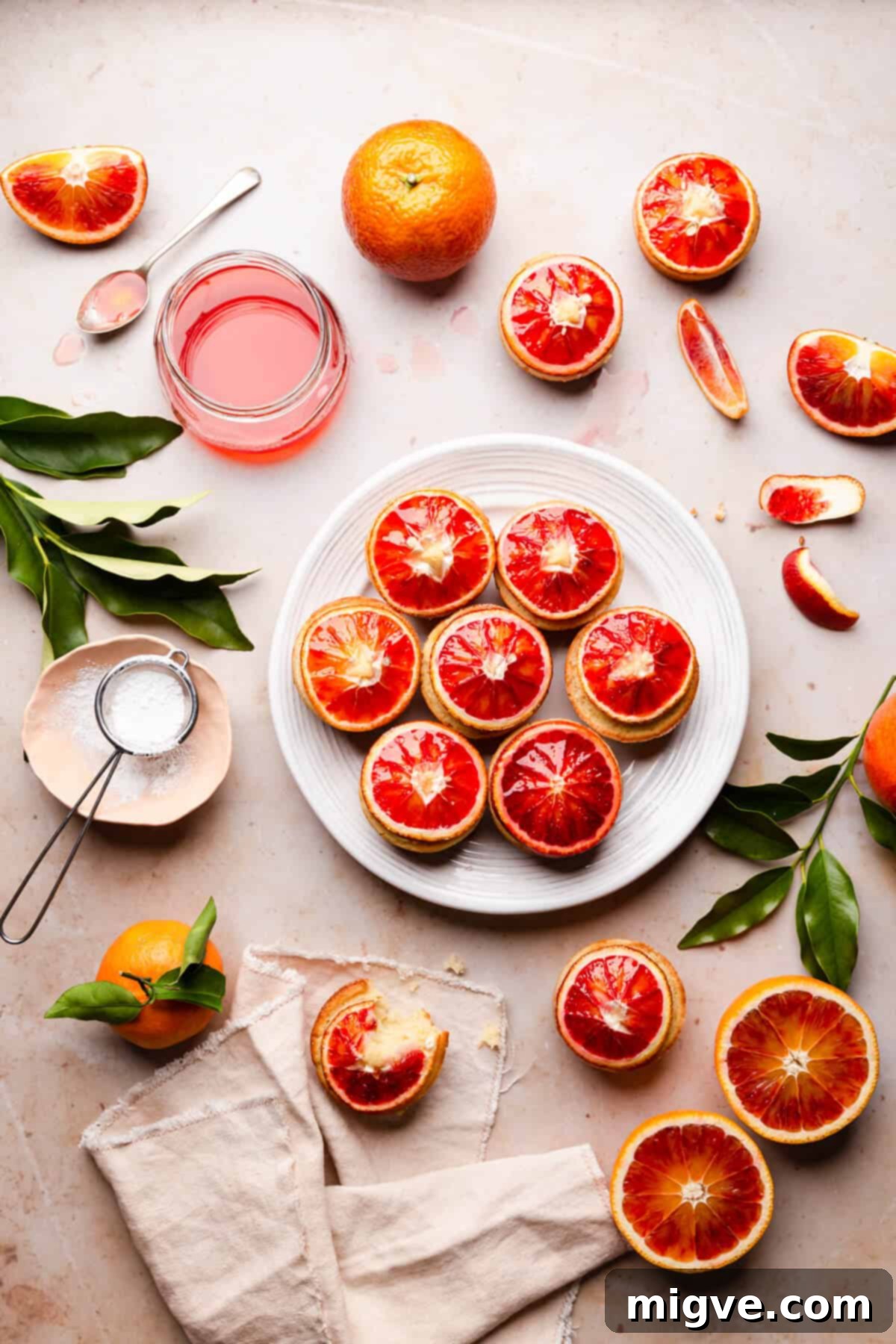 overhead view of blood orange and semolina cakes on a large white plate and some blood orange slices around it