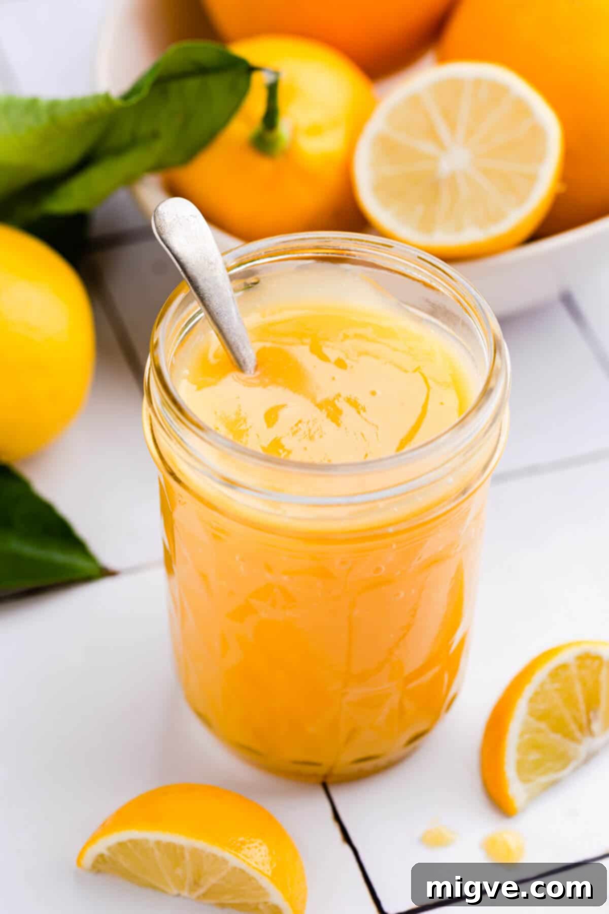 Handcrafted Lemon Zest Delight 2 45 degree angle shot of a jar with citrus curd and small spoon inside of the jar