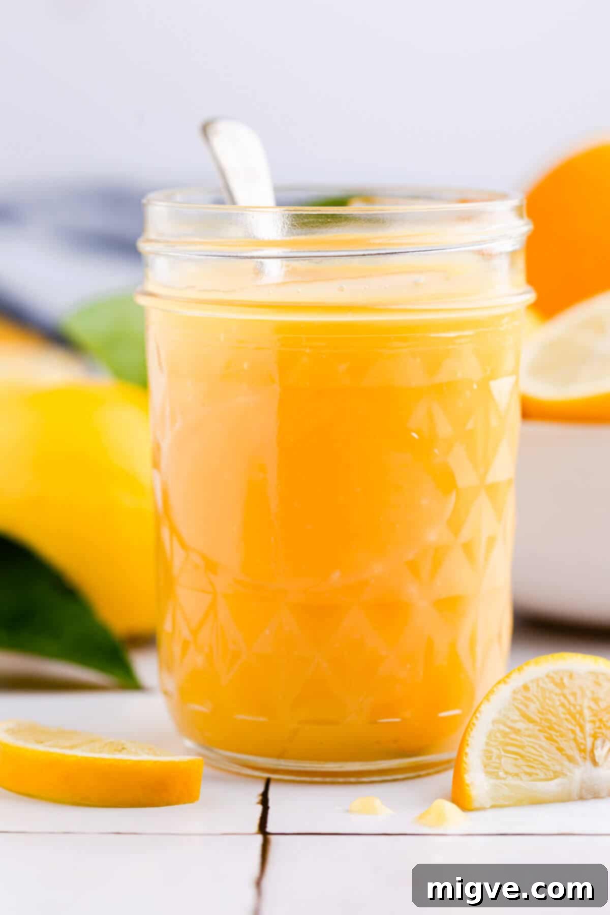 Handcrafted Lemon Zest Delight 12 straight ahead super close up of a glass jar with homemade lemon curd and spoon inside