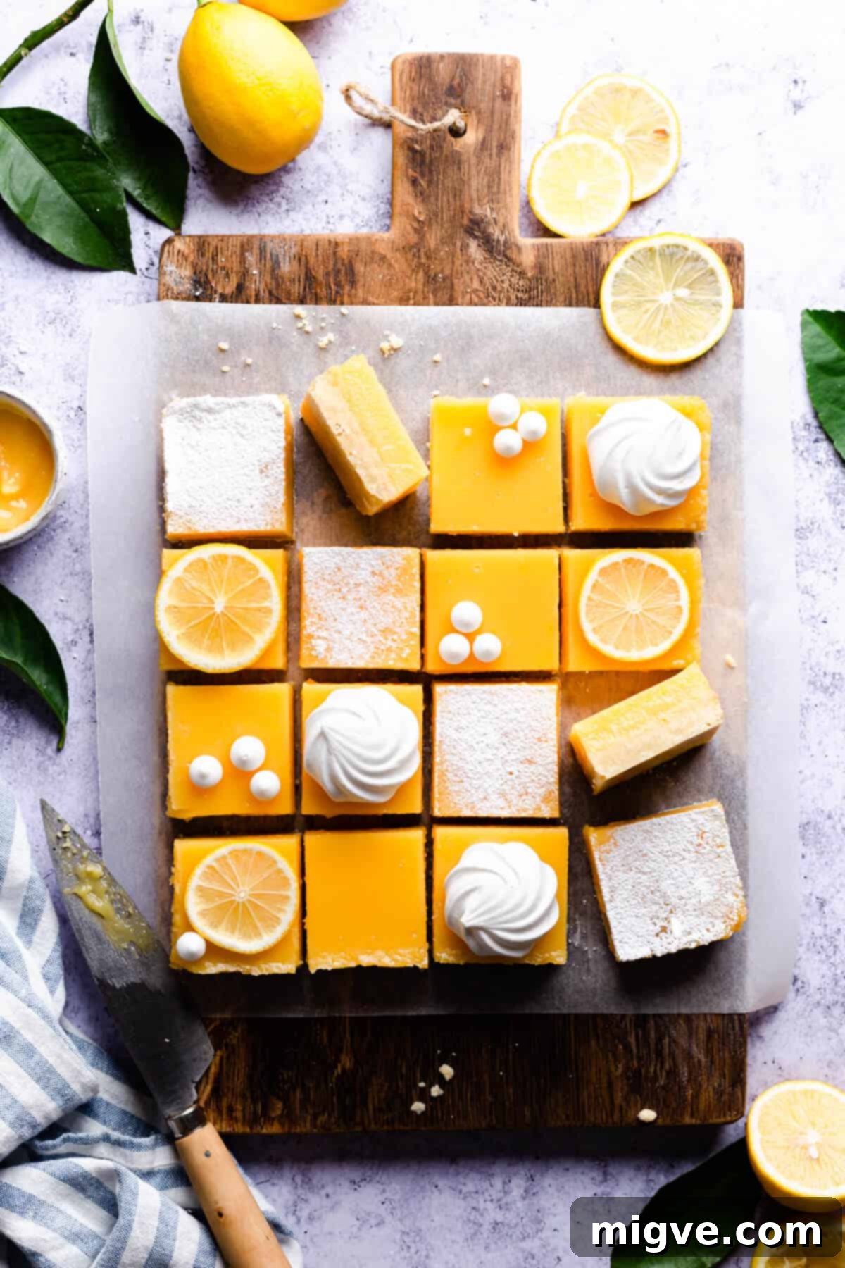Overhead shot of lemon bars cut into squares and topped with vibrant lemon slices and delicate meringues, beautifully presented.