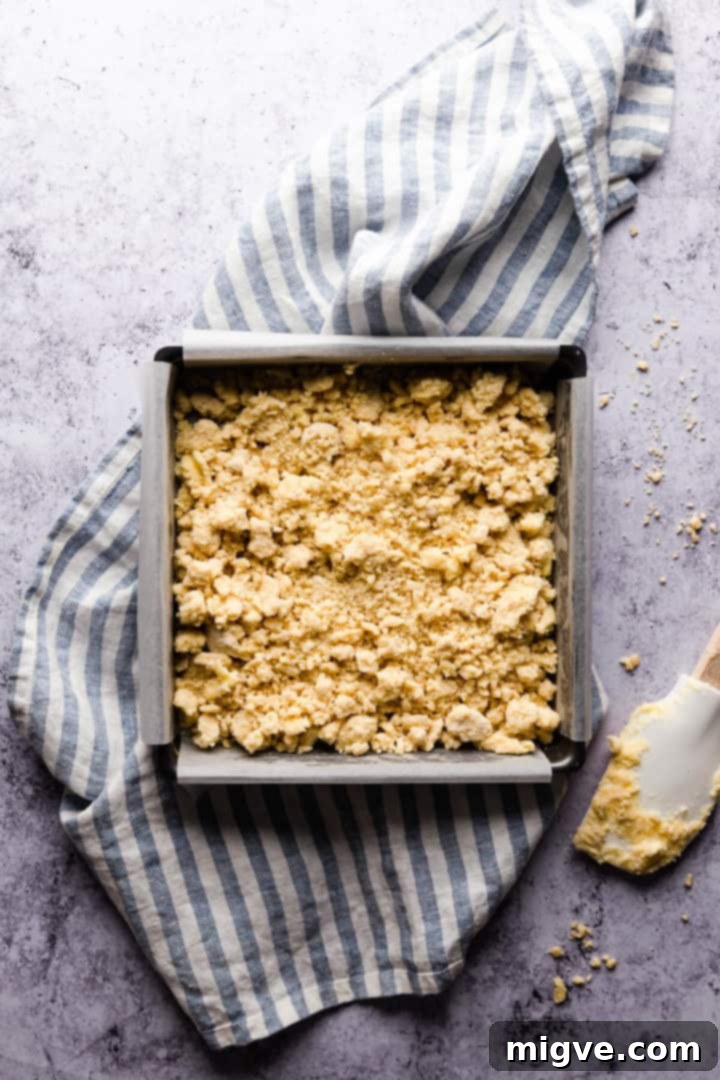 Top view of a square baking tin with unbaked shortcrust base, ready for pressing.