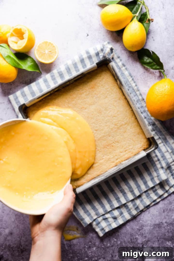 Overhead shot of a person pouring the luscious lemon curd filling on top of the golden shortcrust base.