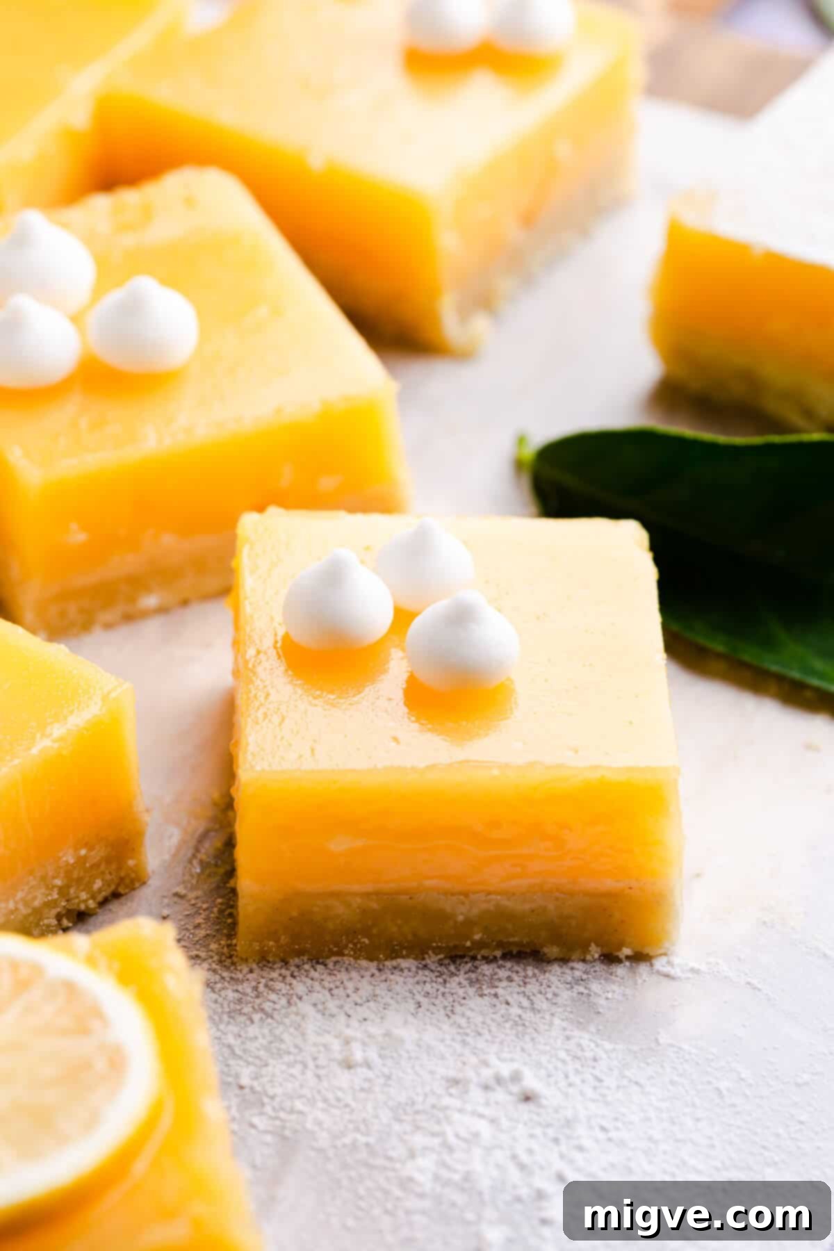 45-degree angle close up at a square lemon curd slice with mini meringues on top, showcasing its vibrant color and delicate texture.