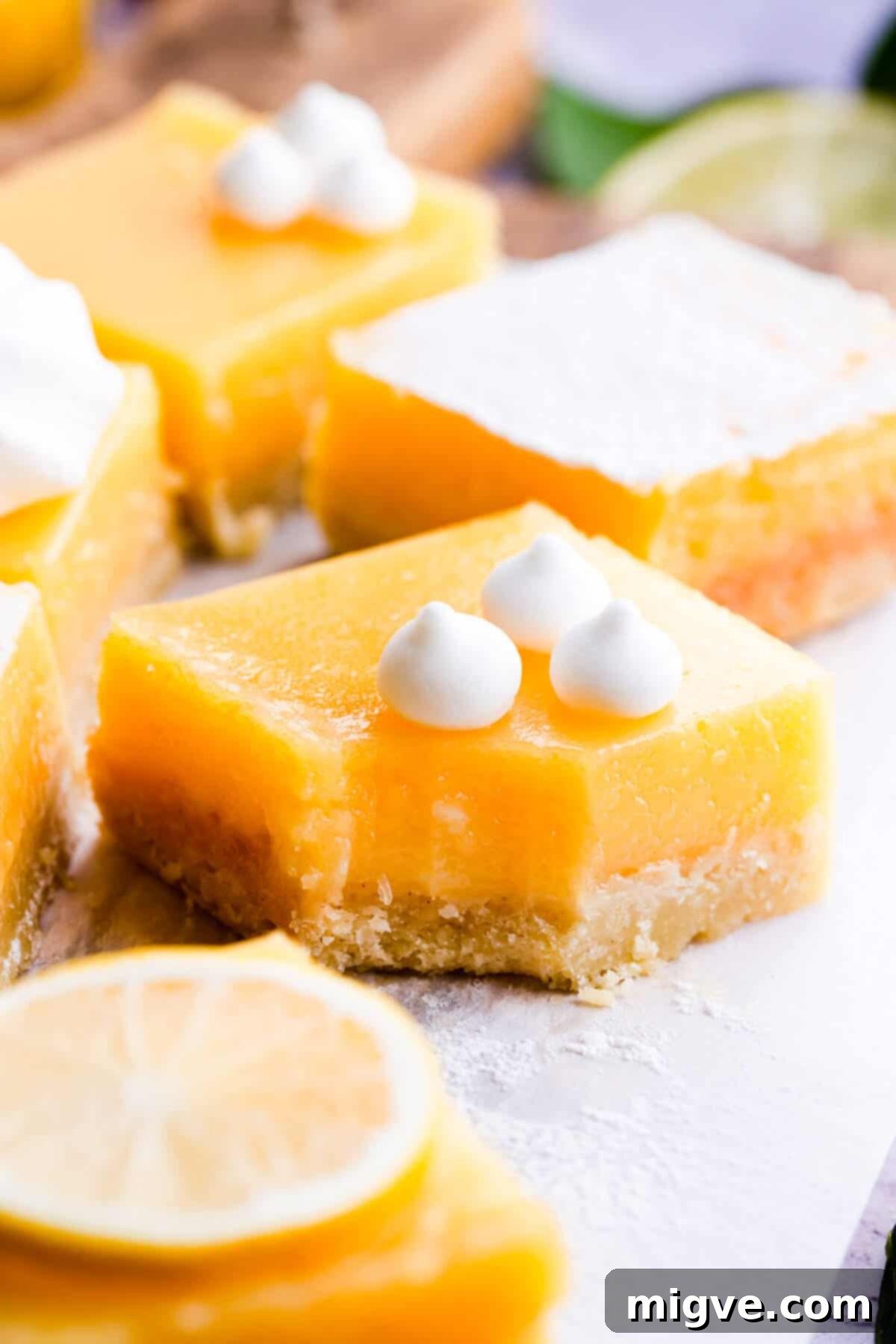 Side angle super close up at a lemon curd slice with a bite taken out, revealing its rich, creamy filling and buttery crust.