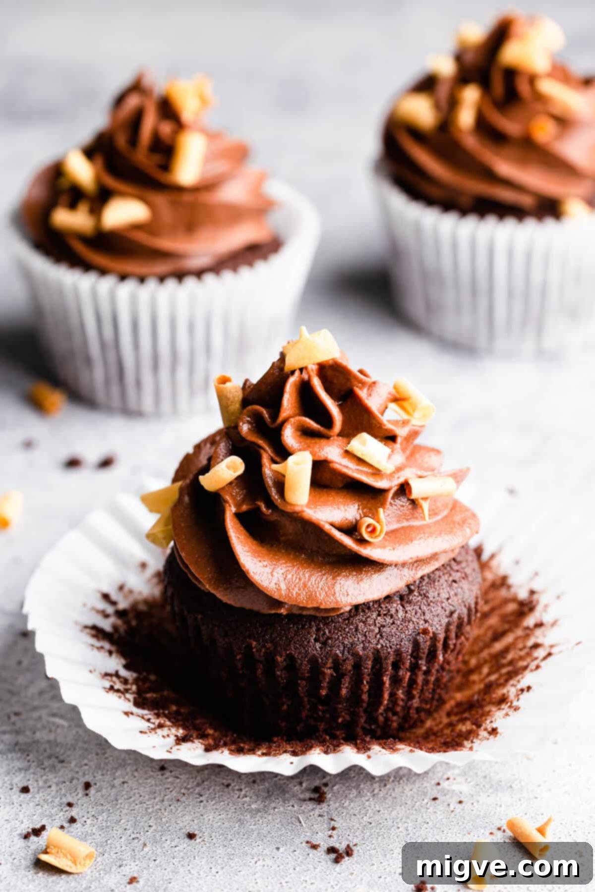 Close up shot of a single chocolate cupcake with buttercream, beautifully unwrapped from its paper case, revealing its moist texture.