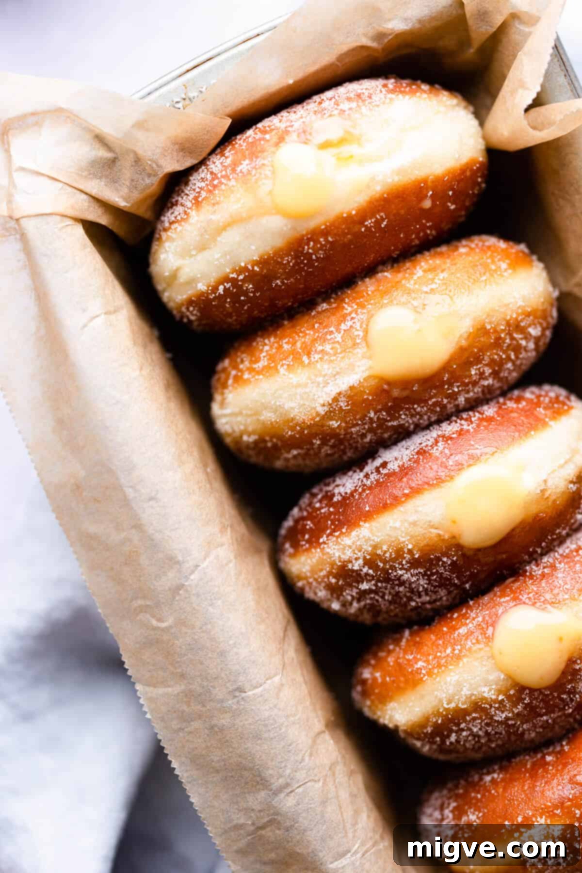 Handcrafted Doughnut Bliss 2 Top-down, super close-up view of perfectly golden-brown small batch doughnuts, generously filled with luscious blood orange curd and coated in glistening sugar crystals, inviting a mouth-watering experience.