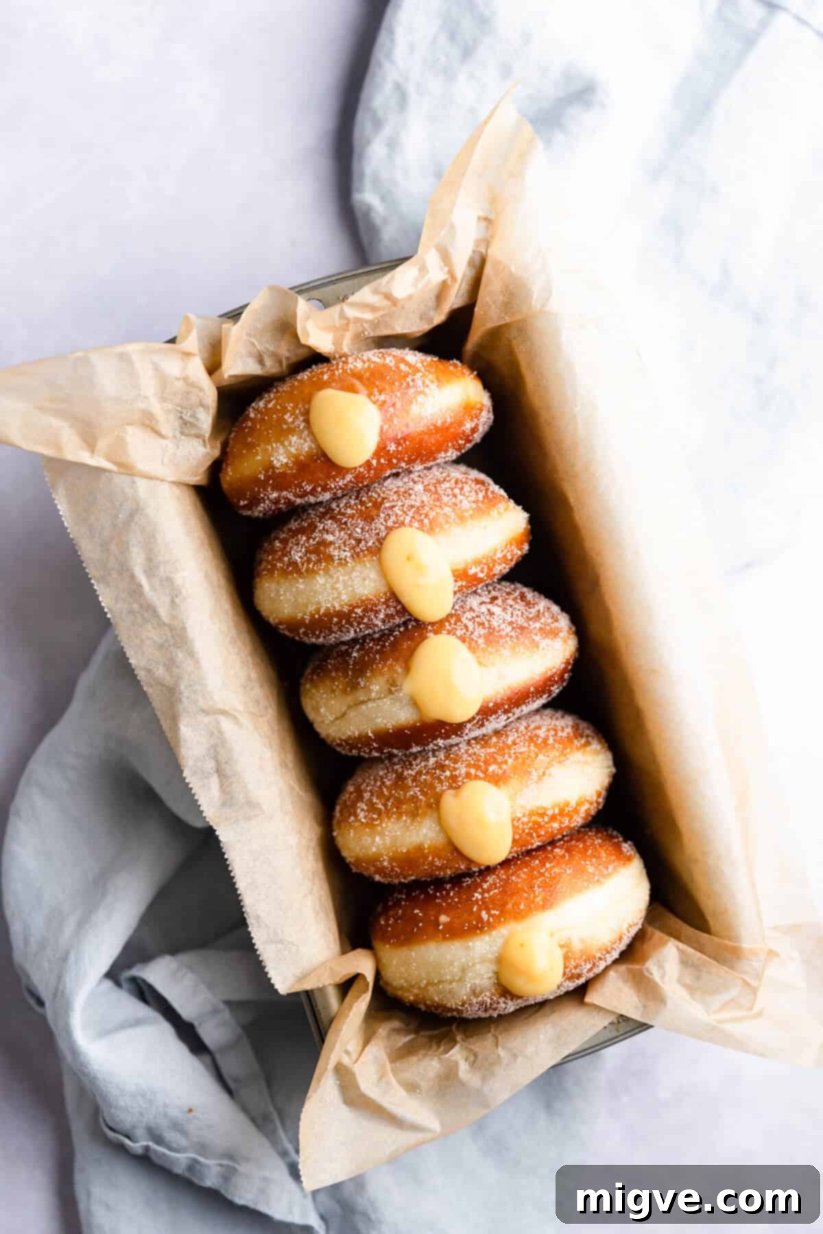 Handcrafted Doughnut Bliss 11 An inviting overhead view of a freshly prepared batch of small batch doughnuts, generously filled with vibrant blood orange curd, dusted with sugar, and ready for serving.