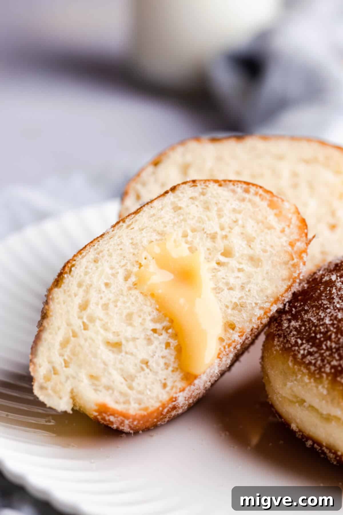 Handcrafted Doughnut Bliss 4 A 45-degree angle close-up photograph of a homemade doughnut cut in half, clearly revealing the rich, vibrant blood orange curd filling oozing from the soft, pillowy interior.
