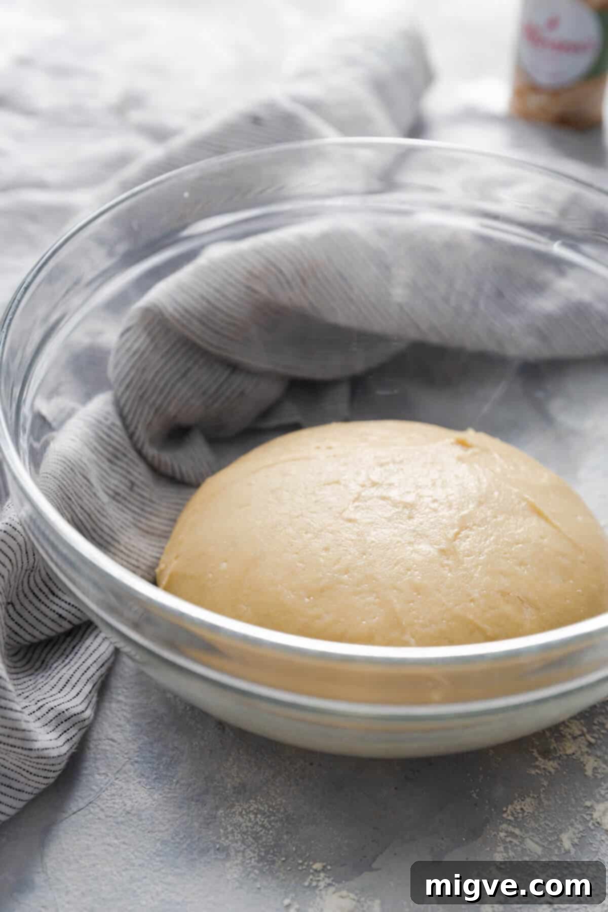 Handcrafted Doughnut Bliss 5 Side angle close-up photo of a glass bowl containing a light, airy dough, visibly risen and ready for the next stage of doughnut preparation.