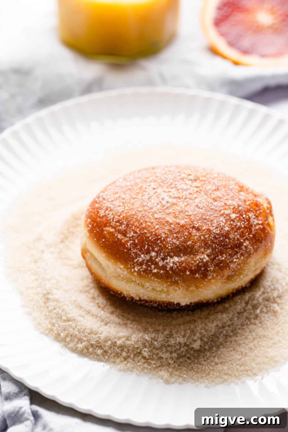 Handcrafted Doughnut Bliss 8 Side angle close-up shot of a single homemade doughnut resting on a plate, generously coated in shimmering sugar, ready to be enjoyed.