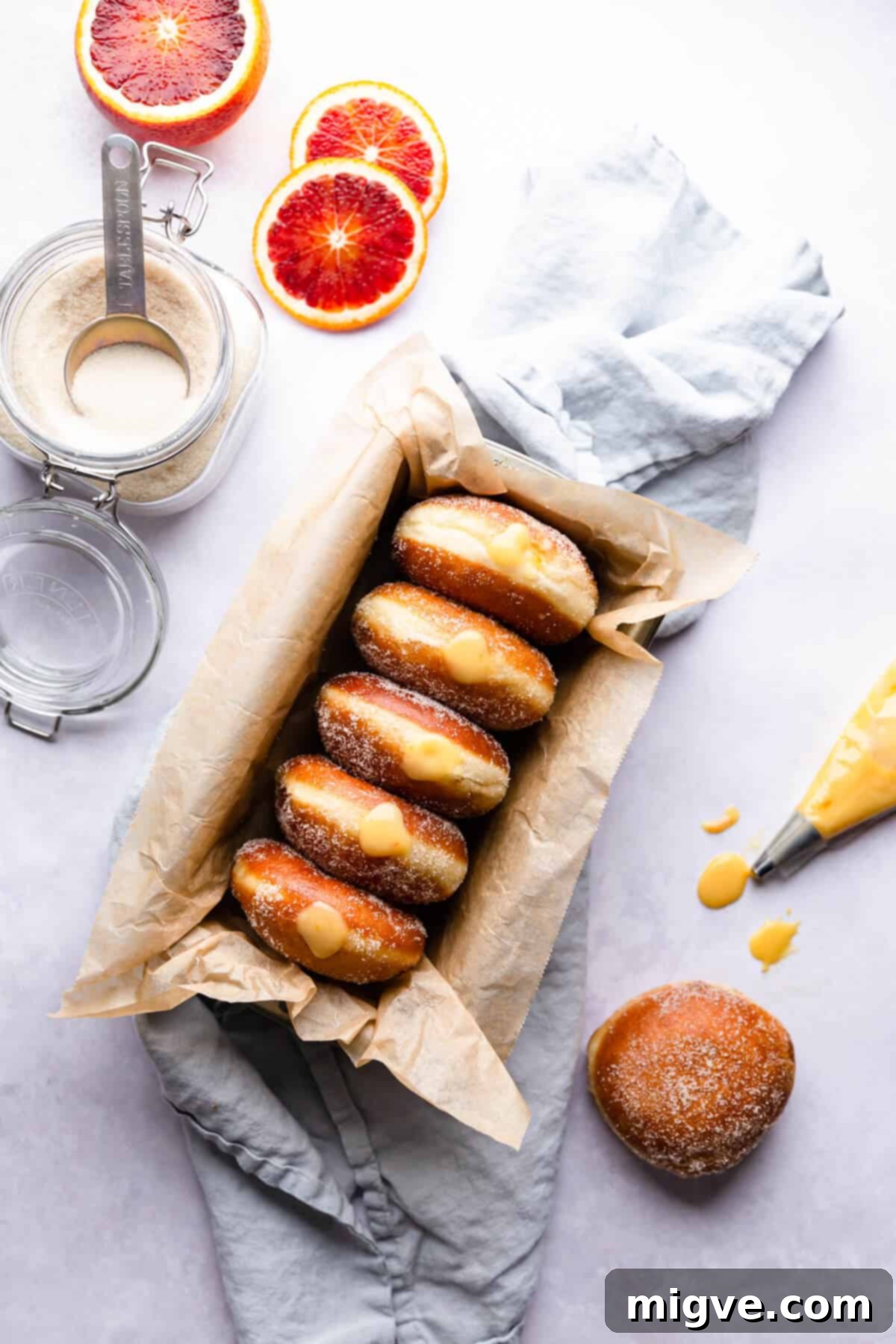 Handcrafted Doughnut Bliss 9 Top-down view of five beautifully filled doughnuts, each bursting with vibrant blood orange curd, with one additional plain doughnut on the side, highlighting their irresistible nature.