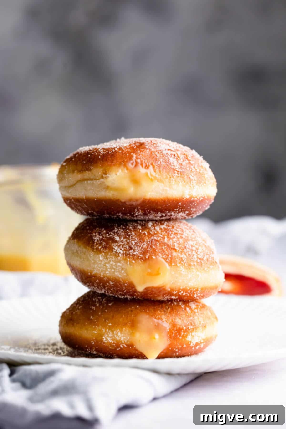 Handcrafted Doughnut Bliss 10 A straight-ahead close-up of three exquisite homemade doughnuts, plump with blood orange curd filling, artfully stacked on top of each other, showcasing their generous filling and inviting texture.