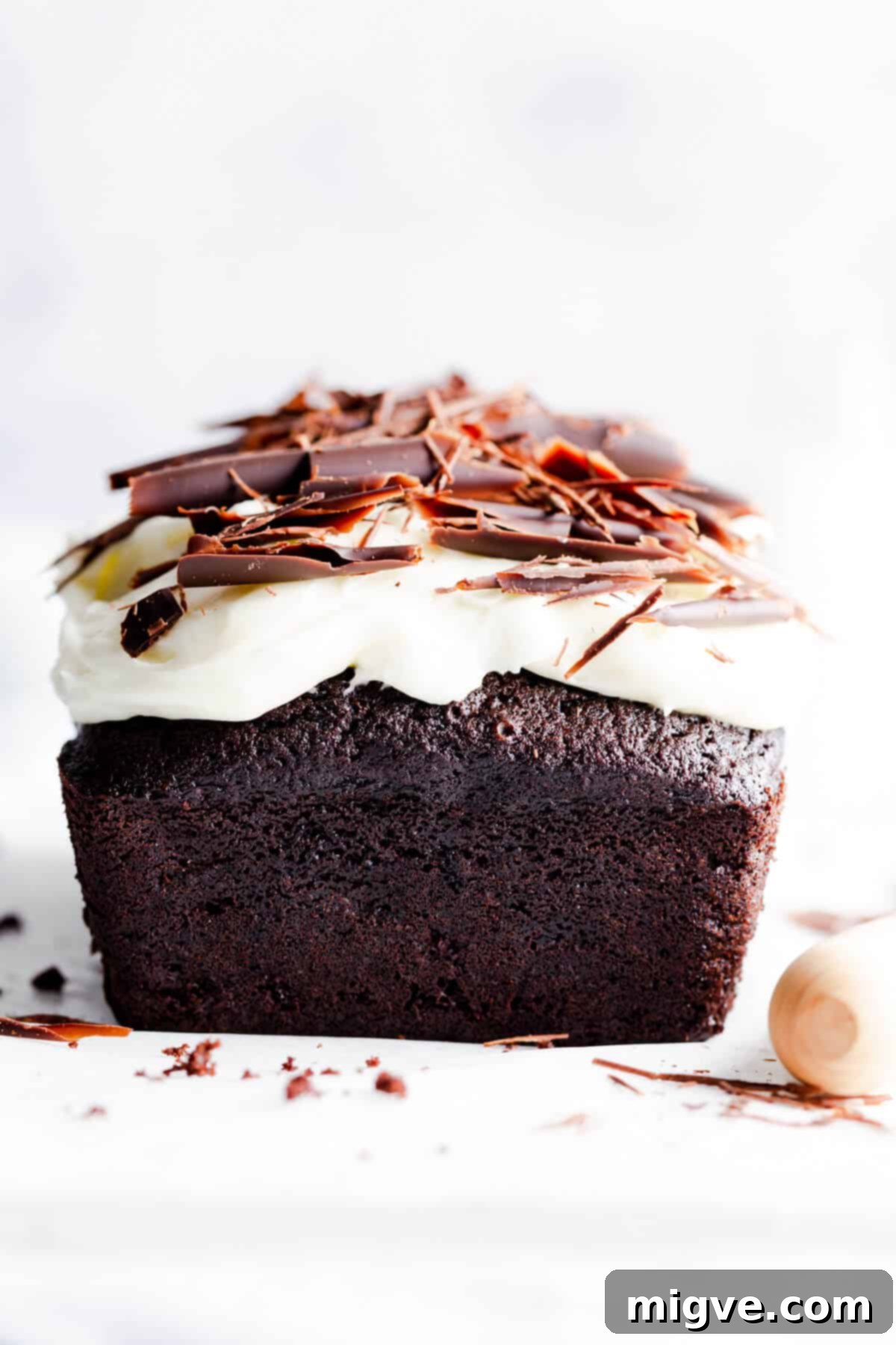 straight ahead super close up photo of chocolate cake with cream cheese frosting and chocolate curls on top