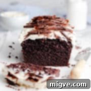 Guinness chocolate loaf cake topped with frosting and chocolate curls