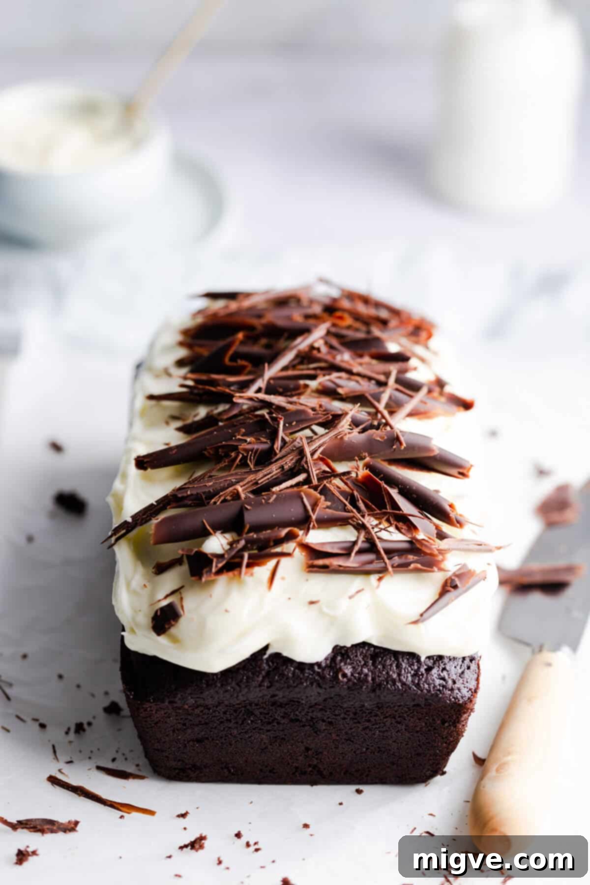 45 degree angle photo of chocolate loaf cake with frosting and chocolate curls